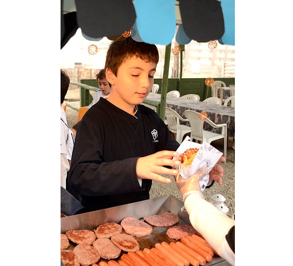 niño comiendo su hamburguesa en evento deportivo en colegio