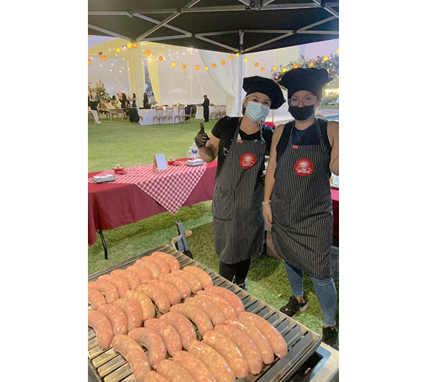 mujer preparando hamburguesas en un evento sobre una plancha en carrito snack